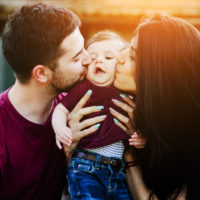 A couple kissing their baby