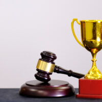 Judge's gavel and trophy on white background. Symbol for jurisdiction. Law concept a wooden judges gavel on table in a courtroom or law enforcement office