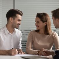 Young happy married family couple making decision before signing contract.