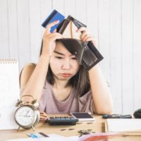 depressed Asian woman having problem with debt hand holding empty wallet and credit card depressed Asian woman having problem with debt hand holding empty wallet and credit card