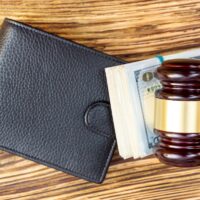 Judges hammer with folded dollars and wallet on the table. Top view.