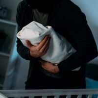 Cropped view of kidnapper in black clothes holding infant child Cropped view of kidnapper in black clothes holding infant child