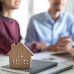 Young family couple talking with property real estate agent abou