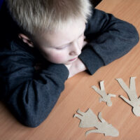 Confused child with broken paper family, family problems, divorce, custody battle, suffer concept Confused child with broken paper family, family problems, divorce, custody battle, suffer concept