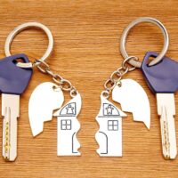 Keys with matching split house and heart keychains on a wooden table. Splitting assets in a divorce. Keys with matching split house and heart keychains on a wooden table. Splitting assets in a divorce.