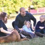 Single father walks with his three daughters of different ages and two pets dogs German boxer. Concept of lonely education, single parent family