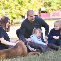 Single father walks with his three daughters of different ages and two pets dogs German boxer. Concept of lonely education, single parent family